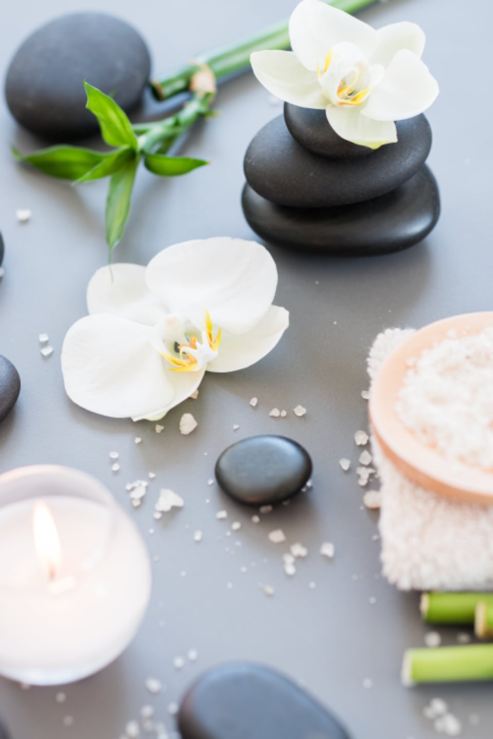 White orchid, bath salt and massage stones on a grey surface