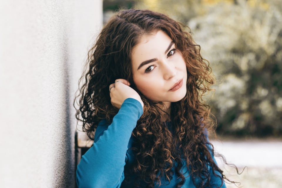 Woman with long curly hair touching her hair