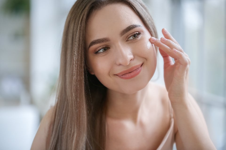 Woman touching her cheek and smiling in a bright bathroom