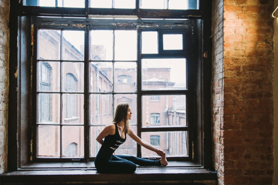 Woman stretching on the floor in front of a large window