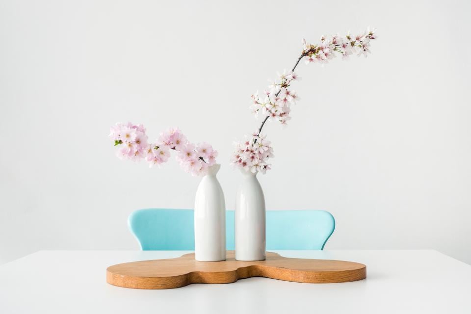 Two white vases with cherry blossom branches on a table