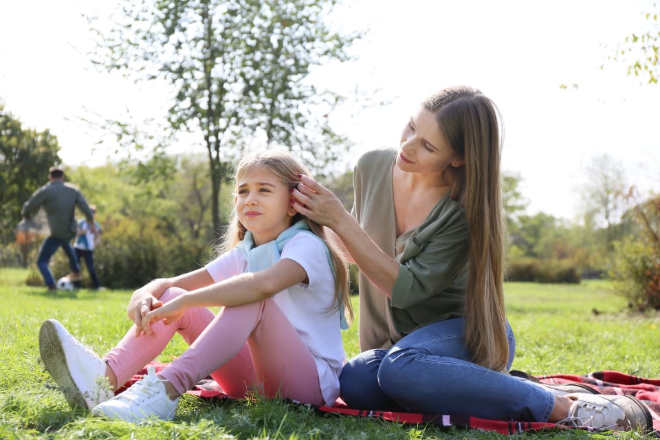 Mother and daughter sitting together on the grass in a sunny park